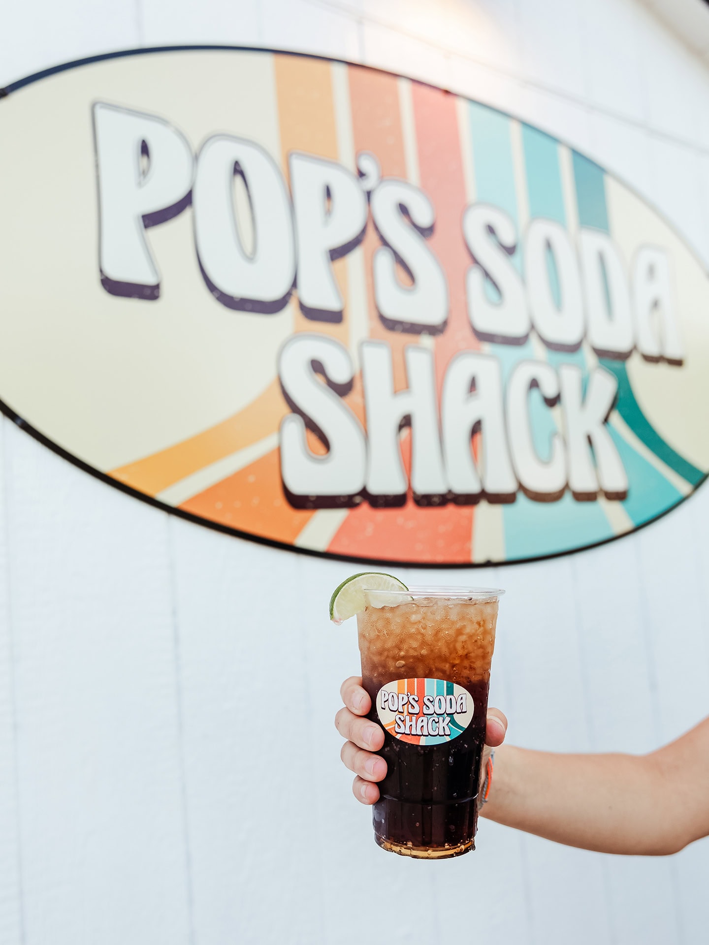 Vibrant soda in a clear cup with a lime wedge at Pop’s Soda Shack.